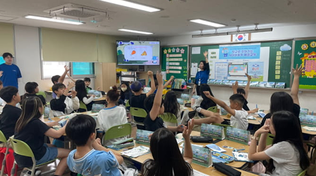 Elementary school students raising their hands during a digital education class.
